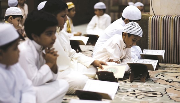 Bahraini Muslim boys read the Holy Quru2019an during the holy fasting month of Ramadan at a mosque in the village of Sanabis, west of Manama.