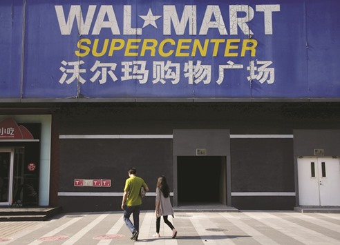 Pedestrians walk past a signboard of Wal-Mart at its branch store in Beijing. The US firm sold its Chinese online grocery store in return for a stake in the countryu2019s No 2 e-commerce firm, ripping up its previous strategy in efforts to cure ailing sales in one of the worldu2019s toughest retail markets.