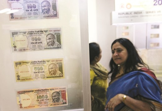 People walk past currency notes displayed in an exhibition of the Reserve Bank of India in Mumbai (file). The rupee closed down 0.3% to 67.52 a dollar yesterday.