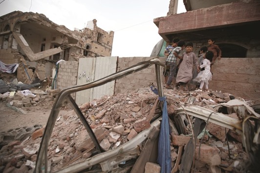 Children play next to houses destroyed during a vigil marking one year since a Saudi-led air strike started on a residential area in Sanaa, Yemen, yesterday.