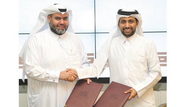 Dr Hassan Rashid al-Derham and Yusuf bin Ahmed al-Kuwari exchange the agreement.