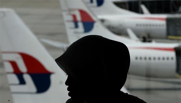 A Malaysian woman is silhouetted against Malaysia Airlines aircraft parked on the tarmac at the Kuala Lumpur International Airport in Sepang. Malaysia hosted a meeting this week with Australia and China to discuss next steps in the fruitless search for MH370.