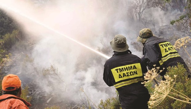 A Cypriot reservist volunteer firefighter and members of the forest department battle a forest fire above the Cypriot village of Evrychou in the Troodos mountain area.