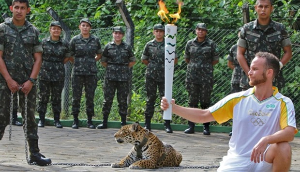 An athlete holds the Olympic Torch by a jaguar --symbol of Amazonia-- during a ceremony in Manaus
