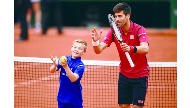 Serbiau2019s Novak Djokovic celebrates next to a ball boy after winning his quarter-final match against Czech Republicu2019s Tomas Berdych at the French Open in Paris yesterday. (AFP)