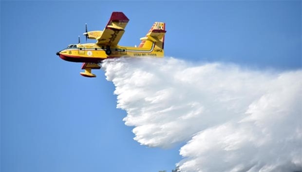An Italian firefighting plane drops water above the Cypriot village of Evrychou in the Troodos mountain area following a forest fire.