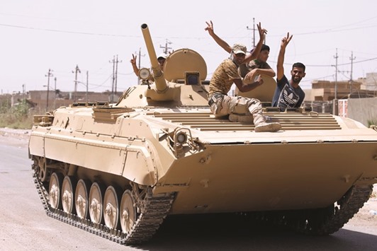 Iraqi soldiers gesture from a top of a tank in Fallujah.