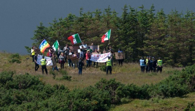 A group of protesters wave Mexican flags on the hillside above the Trump International Golf Links minutes before presumptive Republican presidential nominee, Donald Trump's arrival at the course, north of Aberdeen on the East coast of Scotland.