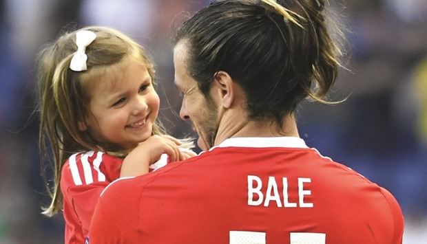 Walesu2019 forward Gareth Bale holds his daughter Alba Viola as he acknowledges the crowds following the teamu2019s 1-0 win over Northern Ireland yesterday.