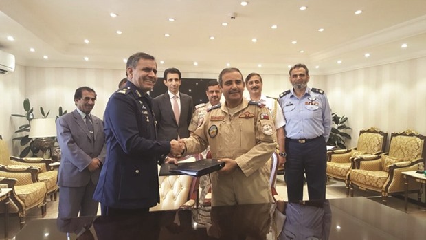 Commander of Al Zaeem Mohamed bin Abdullah Al Attiyah Air College, Brigadier (Pilot) Salem Hamad al-Nabet, and Deputy Chairman of Pakistan Aeronautical Complex (PAC) Air Vice-Marshal Arshad Malik shake hands as they exchange documents after signing the contract, as Pakistanu2019s ambassador Shahzad Ahmed and other officials look on.