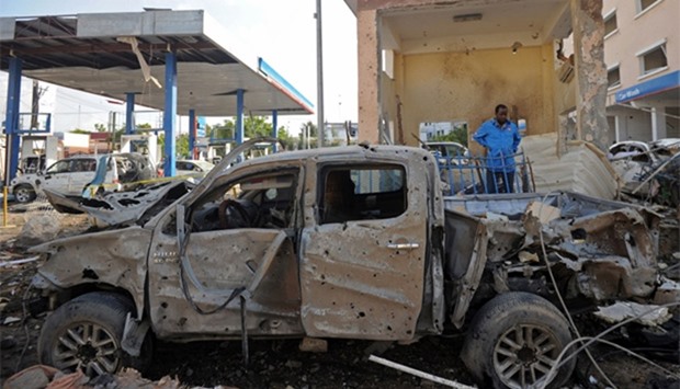 A man stands by a car wreckage in Mogadishu on the scene of the terror attack