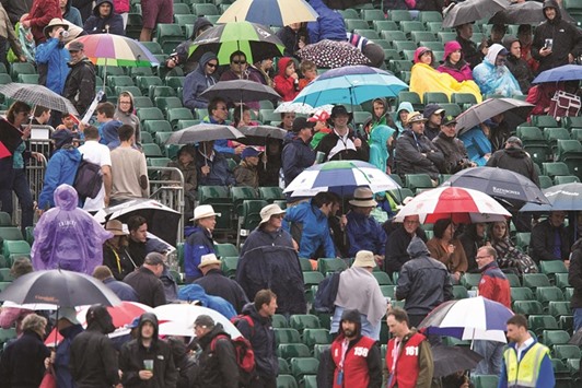 Spectators sit under umbrellas as rain stops play in the third one day international (ODI) cricket match between England and Sri Lanka at Bristol cricket ground in Bristol yesterday.