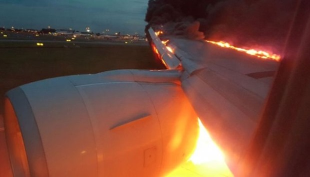 Fire burns on the right wing of a Singapore Airlines Boeing 777-300ER aircraft originally bound for Milan in this still image taken from a handout video, at Changi Airport in Singapore.