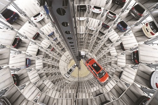 A Volkswagen Golf VII and a VW Passat are loaded in a delivery tower at the companyu2019s plant in Wolfsburg. The settlement filed in the US federal court yesterday calls for the German auto giant to either buy back or fix the cars that tricked pollution tests, and to pay each owner up to $10,000 in cash.