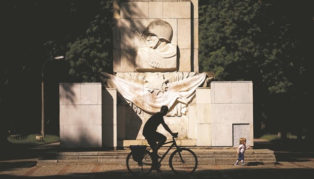 A man rides a bike in front of the monument of the Gratitude for the Soviet Army Soldiers in Warsaw.