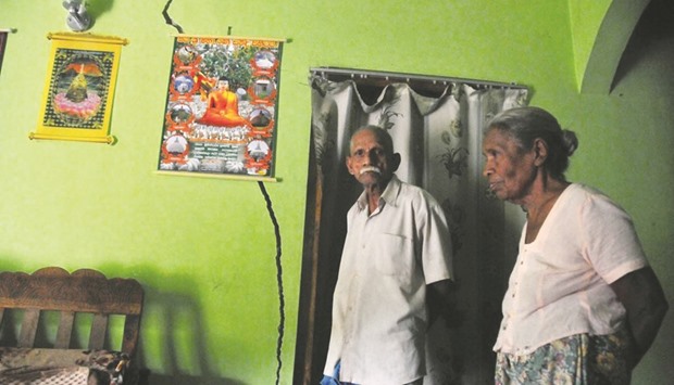 The Karunadasa family stand in their living room, near a crack in their wall that first appeared on May 17, a night when landslides claimed 130 lives in a neighbouring area, and that has been slowly widening since.