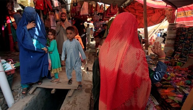 An Afghan woman, clad in a burqa, shops at a market in Peshawar, Pakistan
