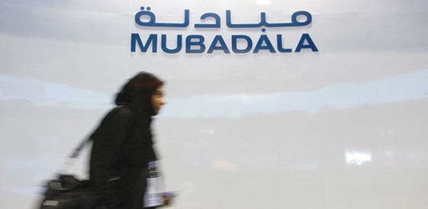 A Mubadala employee walks past the companyu2019s logo at its exhibition booth during the Singapore Airshow (file). The combination of International Petroleum Investment Co and Mubadala Development Company would pool assets of about $135bn and debt of about $42bn, according to Bloomberg calculations.
