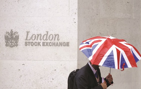 A worker shelters from the rain as he passes the London Stock Exchange in the City of London. The FTSE 100 closed up 3.6% to 6,360.06 points yesterday.
