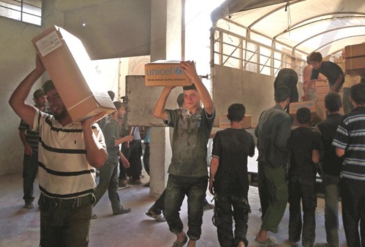 Syrians unload aid boxes from a Syrian Arab Red Crescent truck in Zamalka, a besieged rebel-held town east of the capital Damascus, yesterday.