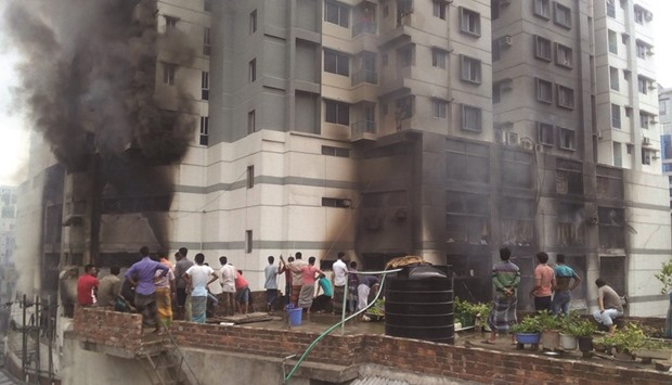 People watching heavy smoke from a fire at a residential multi-story building at Uttar Badda in Dhaka yesterday.