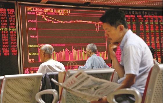 A man reads a newspaper in front of an electronics board at a brokerage firm in Beijing. Shanghai exchange closed 0.1% down yesterday.