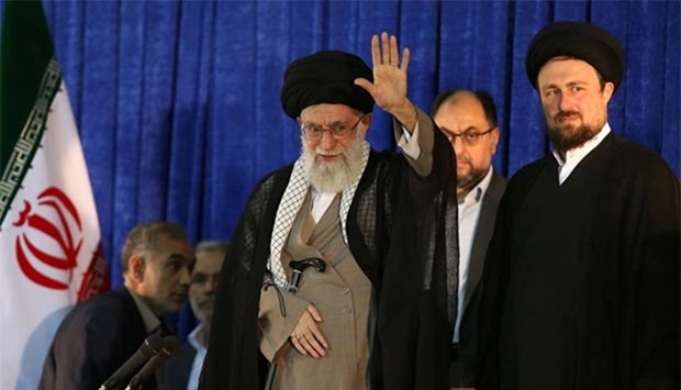 Ayatollah Ali Khamenei waves as he is seen with Hassan Khomeini (right), grandson of Ayatollah Ruhollah Khomeini, during the 27th anniversary of Khomeini's death at his mausoleum in Tehran on Friday.