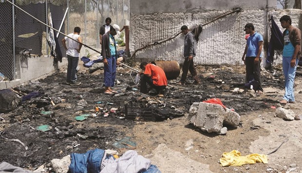 Migrants searching through debris of a torched tent in the Moria detention camp on the Greek island of Lesbos following  clashes between Afghans and Pakistanis migrants.