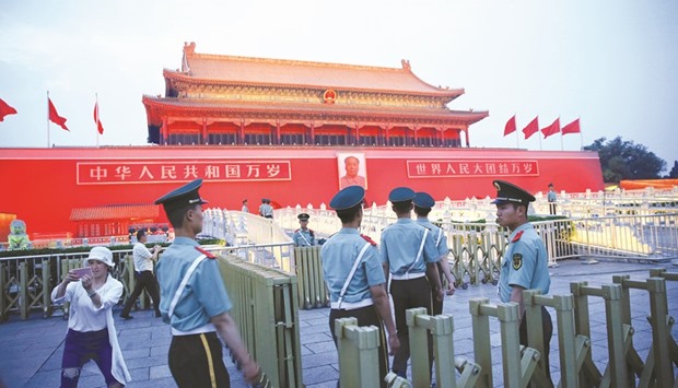 Paramilitary policemen return towards the Tiananmen gate after a flag-lowering ceremony at Tiananmen square in Beijing yesterday.