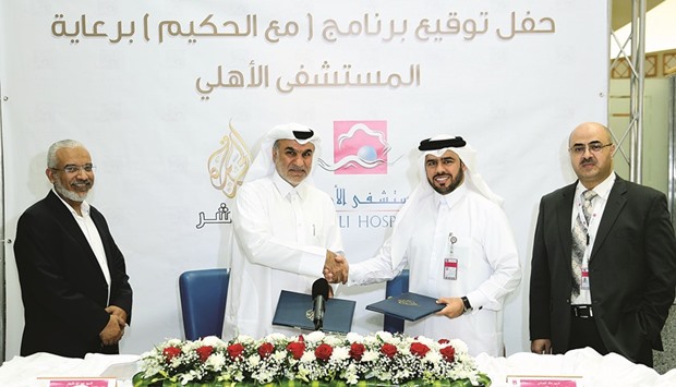 Al-Najjar and al-Emadi shaking hands after signing the agreement as other officials look on.