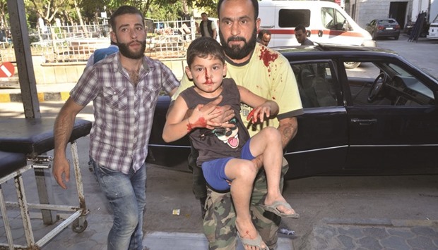 A Syrian man carries a child who was wounded following reported shelling by rebel fighters arrives at a hospital in the Al-Jamiliyah neighbourhood on the government-controlled side of the divided northern Syrian city of Aleppo yesterday.