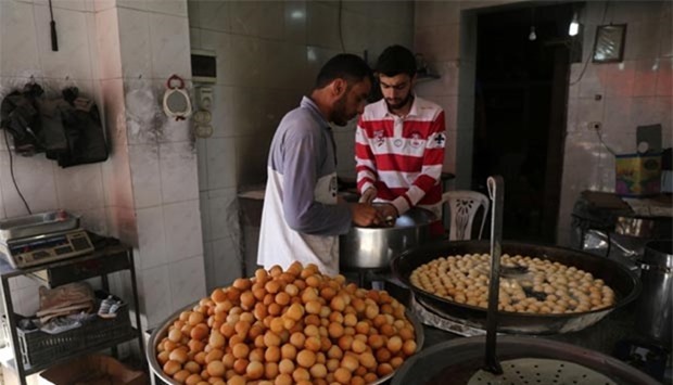 Syrian men prepare sweets at a market in the reble-held district of al-Fardous in Aleppo on Monday, as people shop prior to Iftar on the first day of Ramadan.