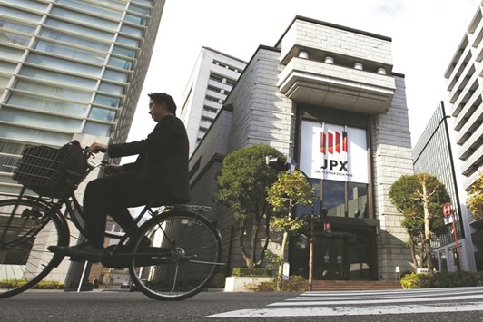 A man cycles past the Tokyo Stock Exchange. The Nikkei 225 closed down 0.4% to 16,580.03 points yesterday.
