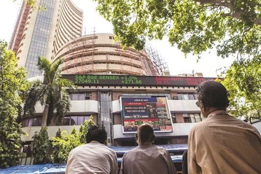 Men look up at an electronic screen displaying stock figures at the Bombay Stock Exchange building in Mumbai. The Sensex closed up 232.22 points to 27,009.67 yesterday, its highest close since October 28, 2015.