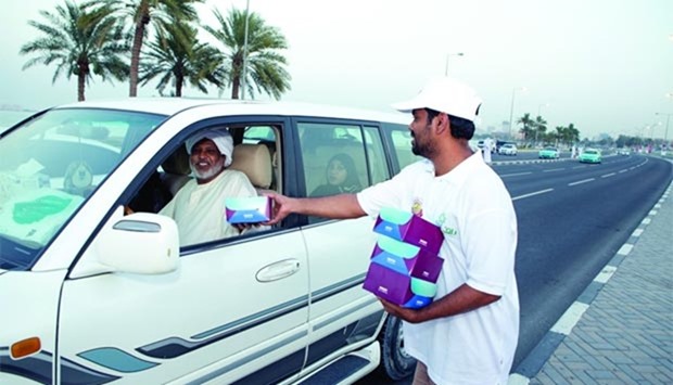 A volunteer distributing Iftar kits to a motorist in Doha