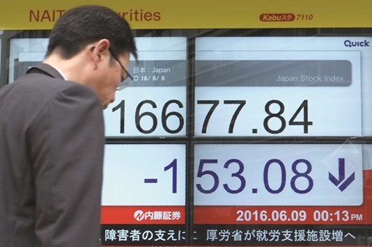 A man walks past an electronic quotation board flashing the Nikkei index in Tokyo. Japanese shares pulled back 1.3% yesterday, hurt by a stronger yen.