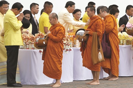 Thai Prime Minister Prayuth Chan-ocha (left) offers alms to Buddhist monks during a ceremony at the Grand Palace to commemorate Thailandu2019s King Bhumibol Adulyadeju2019s 70th anniversary on the throne, in Bangkok, yesterday.