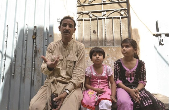 Pakistani schoolgirl Maham (right), who was taught by a teenager who was set on fire by her mother, poses for a photograph alongside classmate Amina (centre) and her father Mohamed Asghar outside the house where their teacher lived in Lahore yesterday.