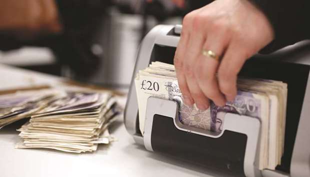 An employee removes 20 sterling pound notes from an automated currency counting machine in London. Sterling slumped to a seven-week low of $1.2636 yesterday.
