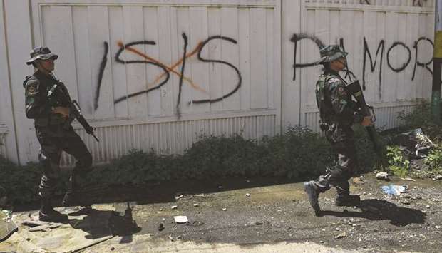 Soldiers walk past Islamic State (IS) group graffiti in Marawi on the southern island of Mindanao yesterday.