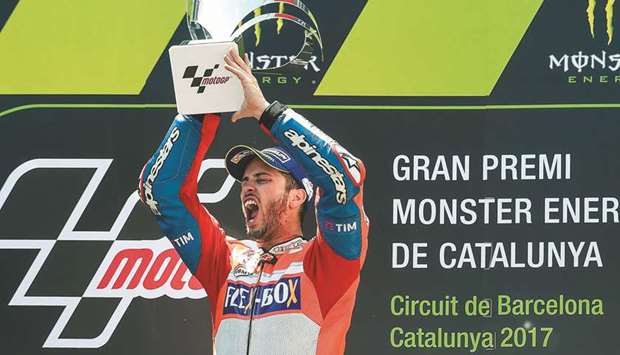 Ducatiu2019s Italian rider Andrea Dovizioso celebrates with the trophy on the podium after winning the Catalunya Grand Prix. (AFP)