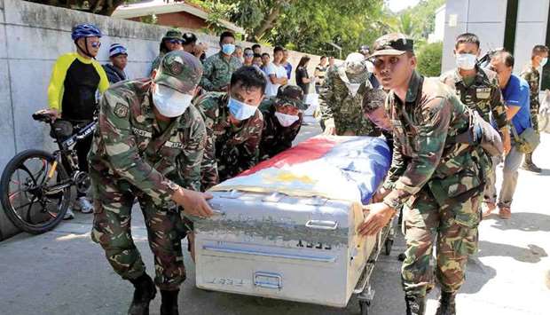 Government soldiers transport a cadaver of a soldier, who was killed during the government troops assault against the insurgents from the Maute group, who seized large parts of the Marawi city, in Iligan, yesterday.