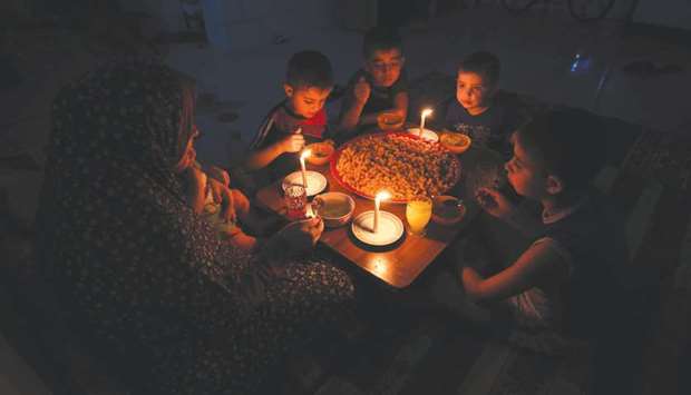 A Palestinian family eats dinner by candlelight at their makeshift home in the Rafah refugee camp, in the southern Gaza Strip, during a power outage.