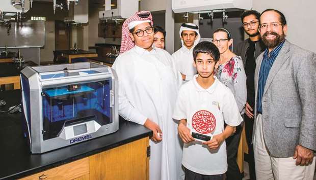 Teachers and students pose after installation of a 3D printer at a school.