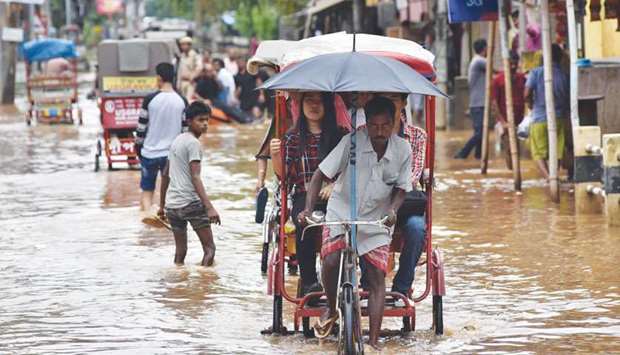 A rickshaw puller transports customers through floodwaters in Guwahati yesterday.
