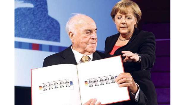 This file photo taken on September 27, 2012 shows Kohl and Merkel posing with stamps featuring him at the German Historical Museum (Deutsches Historisches Museum) in Berlin, during a ceremony celebrating the 30th anniversary of Kohl being elected chancellor. The stamps were issued in honour of Kohlu2019s political achievements.