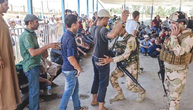 An Iraqi soldier frisks a displaced Iraqi man at a temporary camp in the compound of the closed Nineveh International Hotel in Mosul yesterday.