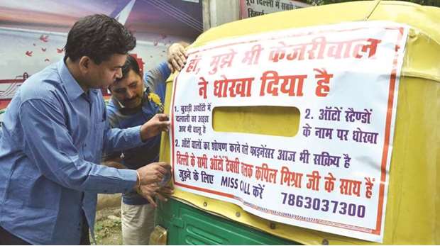 Sacked Delhi Minister Kapil Mishra sticks a poster on an auto-rickshaw as part of a campaign against Chief Minister Arvind Kejriwal in New Delhi yesterday.