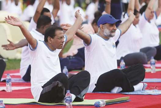 Sri Lankau2019s President Maithripala Sirisena, left, and Indian High Commissioner to Sri Lanka Taranjit Singh Sandhu, right, perform yoga at an event to mark International Day of Yoga in Colombo yesterday.