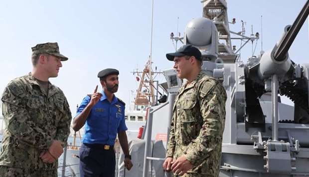 Qatari Navy Chief Co-ordinator Mohamed Dasmal al-Kuwari (cetnre), Jon Anderson (right) and Benjamin Davni of the US Navy are seen on a vessel during a joint military exercise between Qatar and the US navy, in Doha, on June 16.